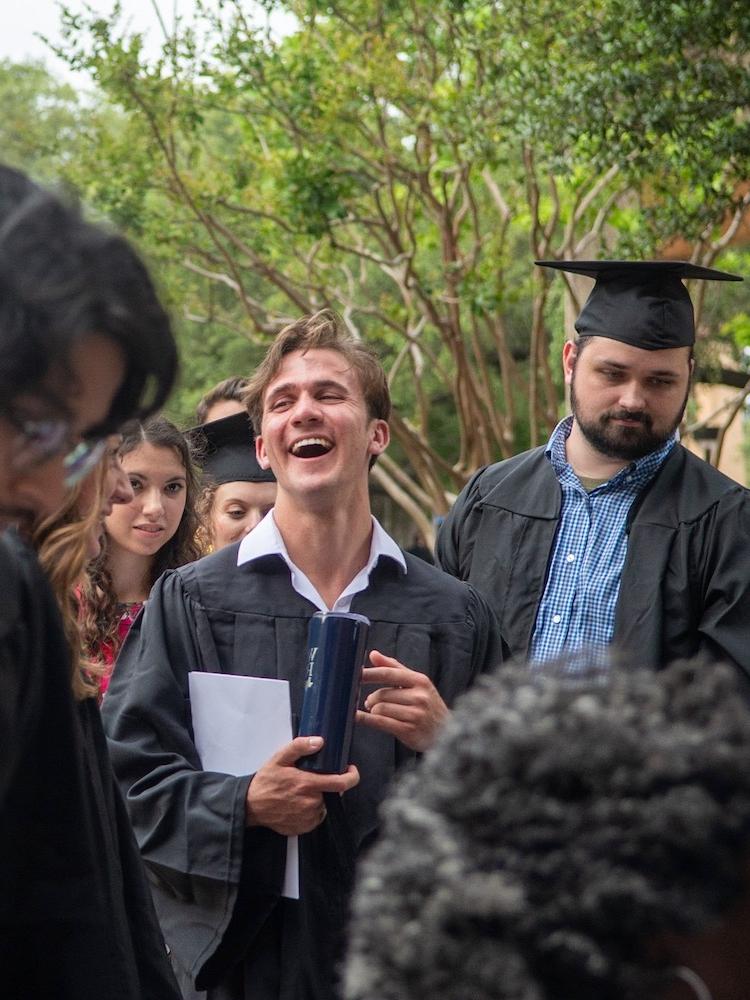 Students in caps and gowns smiling